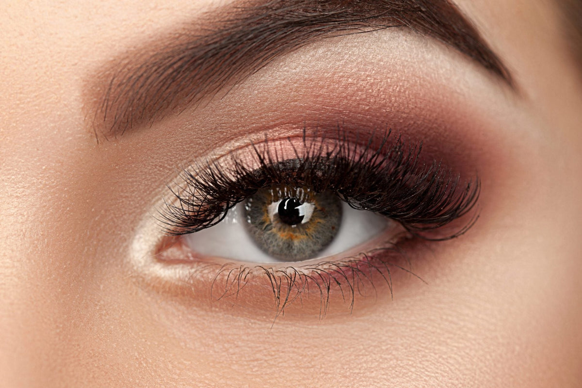 Close-up van een feestelijke ooglook met warme bruine en rozige oogschaduw, shimmer en volle wimpers.
