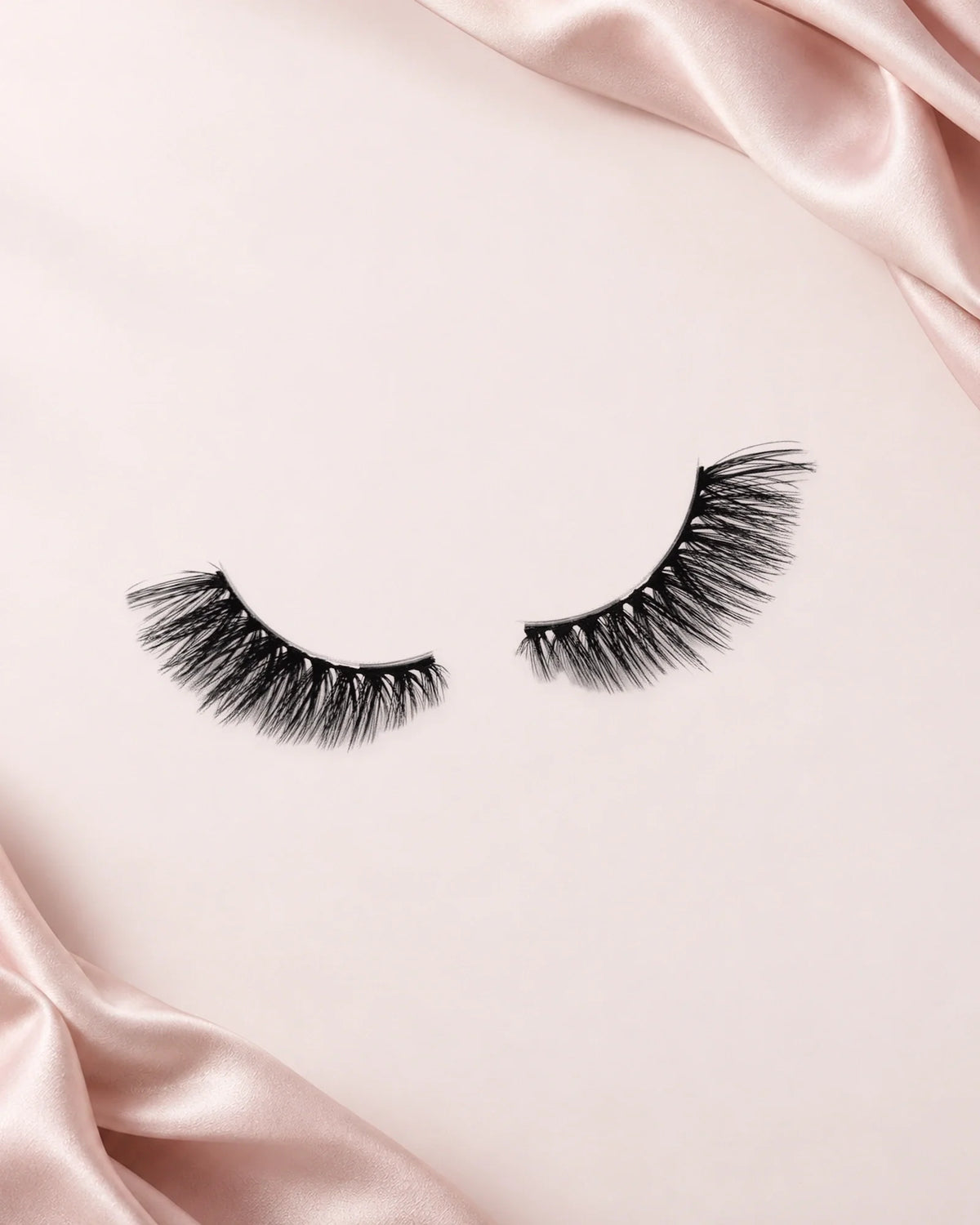 Darling halve wimpers van By Dash Beauty op een lichtroze achtergrond met satijn.