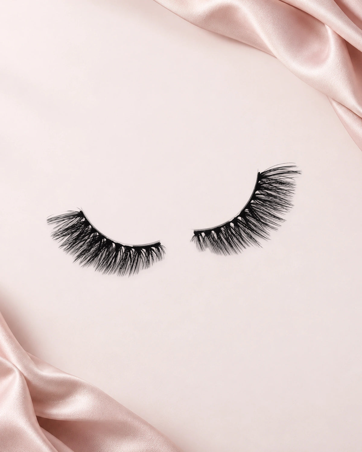 Darling halve wimpers van By Dash Beauty op een lichtroze achtergrond met satijn