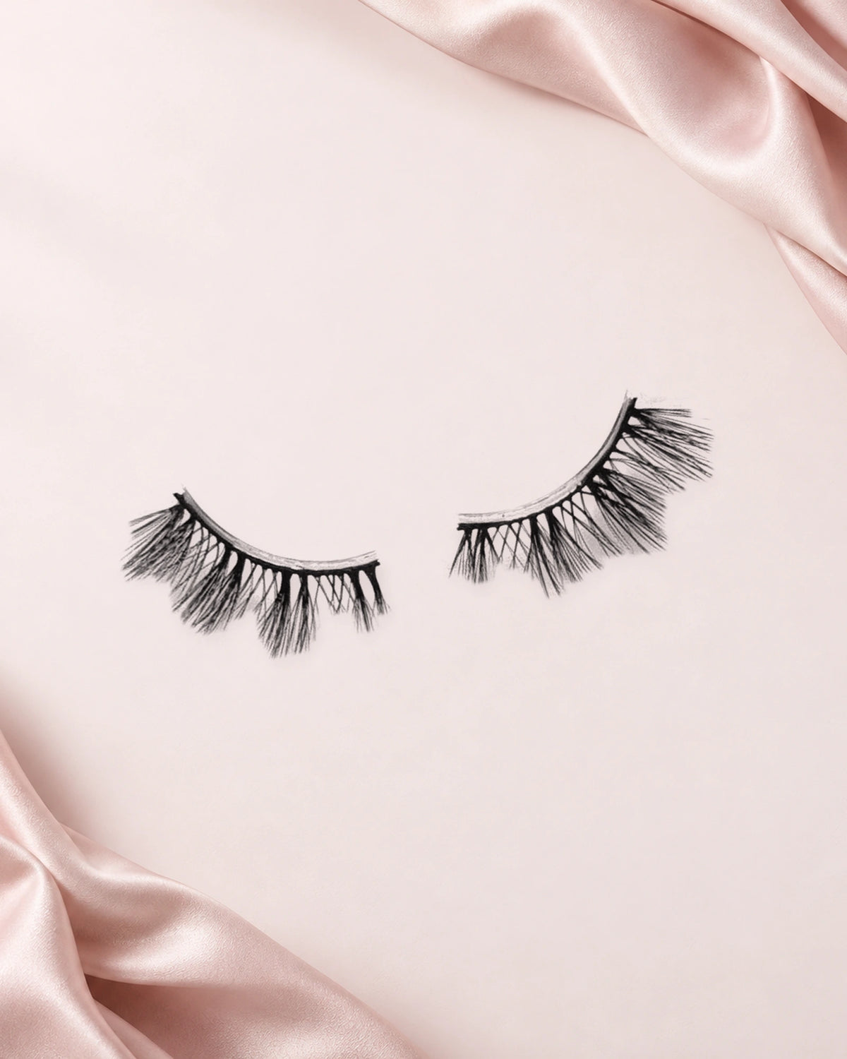 It Girl halve wimpers van By Dash Beauty op een lichtroze achtergrond met satijn