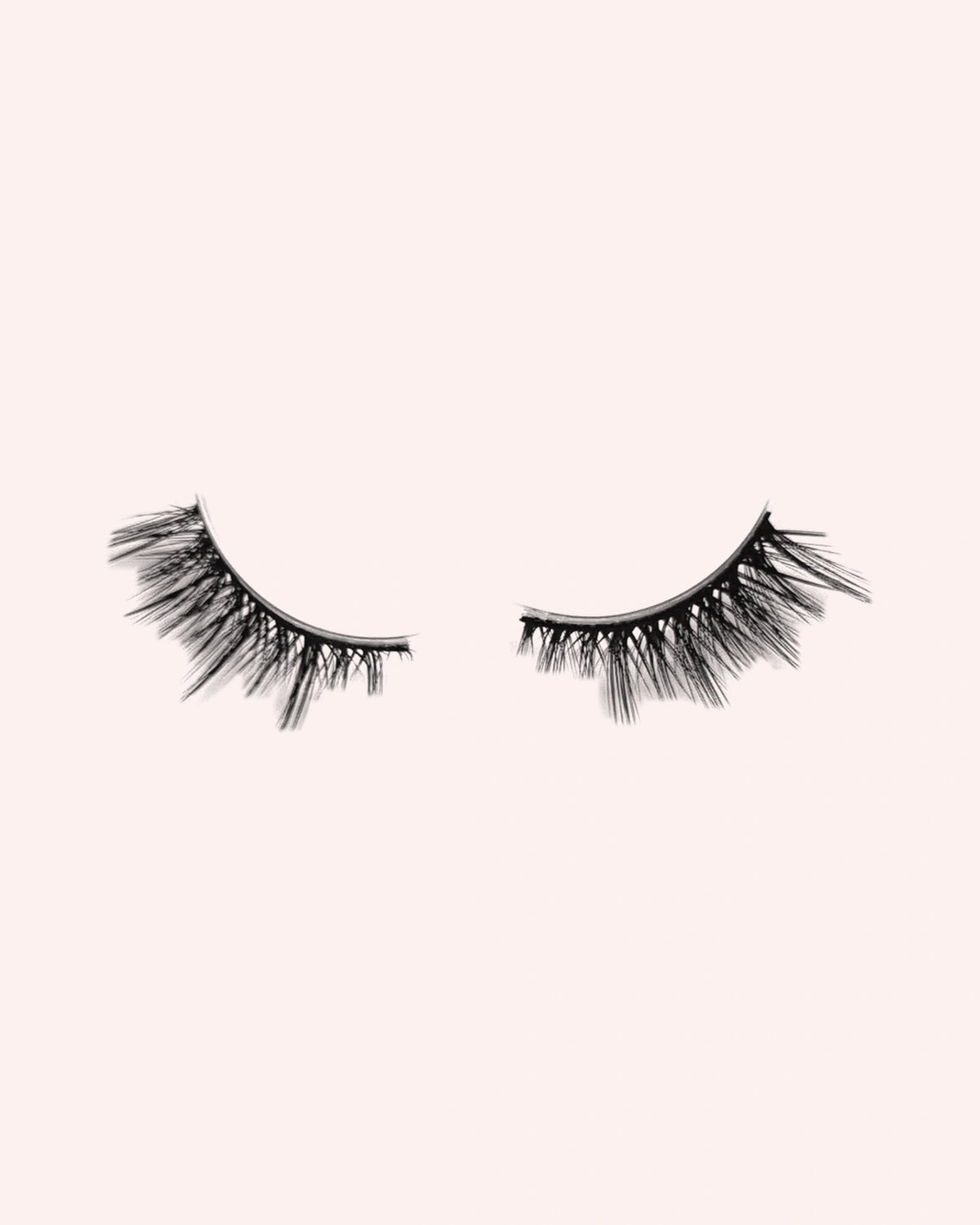 Eén paar Obsessed halve wimpers van By Dash Beauty op een lichtroze achtergrond