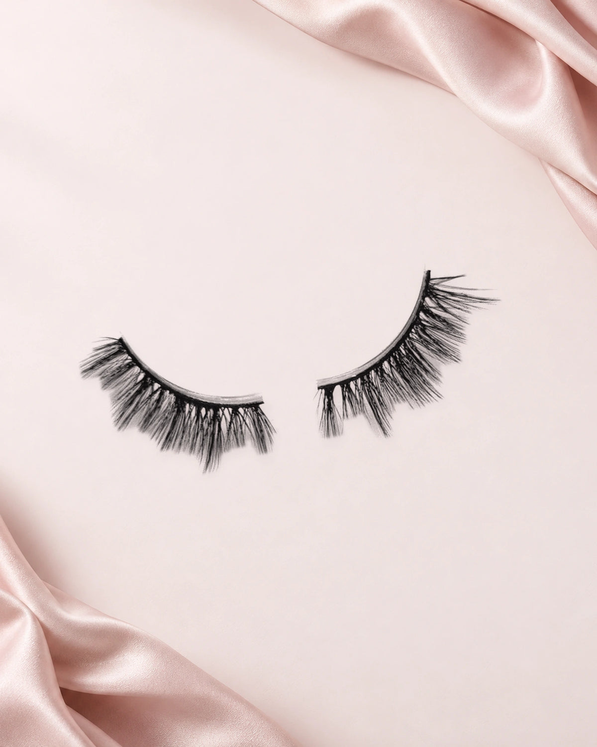Pretty Please halve wimpers van By Dash Beauty op een lichtroze achtergrond met satijn